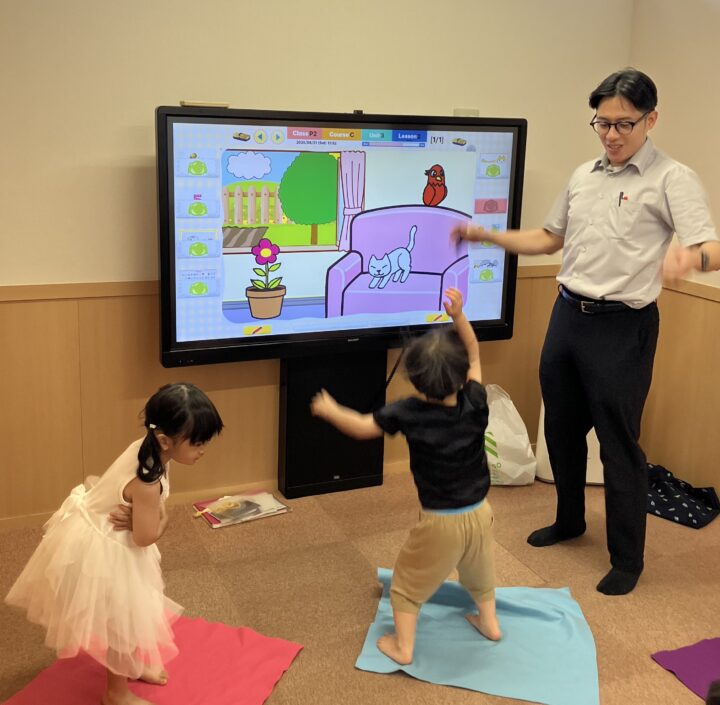手の動きが発達段階にある低年齢のお子さんの場合 ★視覚的な認識を促し、★身体運動を伴う活動をする ことが重要です！ この時期のお子さんは、体を使うことで学習したことが記憶に残りやすいためです。  大画面のタッチパネルを使って、キャラクターや先生の動きに合わせながら 歌って踊るアミティーのレッスンはピッタリ！亀有校のこども英語・英会話教室アミティー